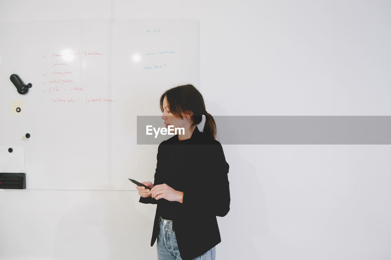 Mid adult businesswoman holding felt tip pen while standing in creative office