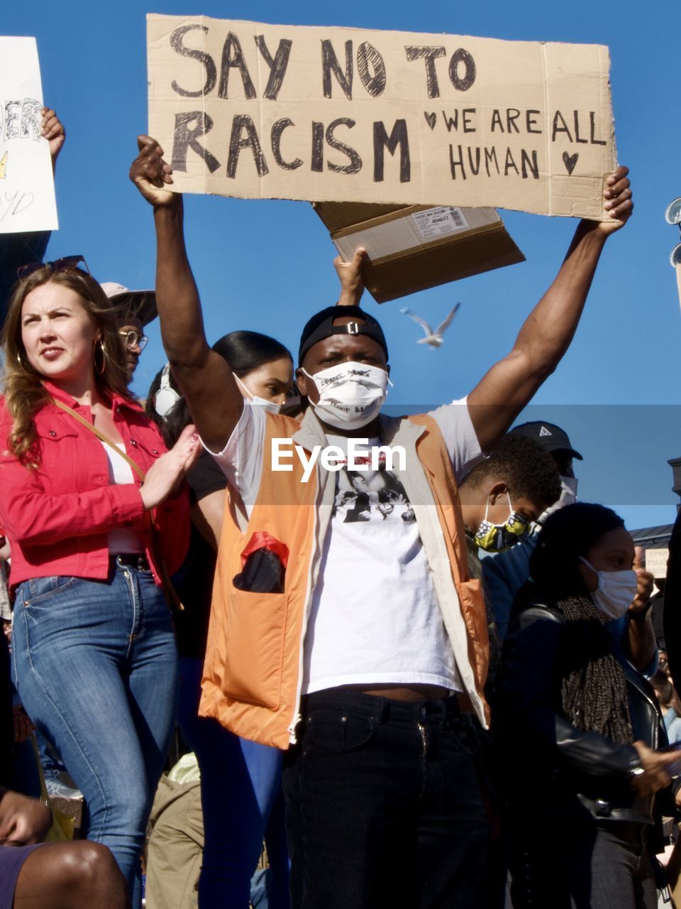 REAR VIEW OF PEOPLE WALKING ON STREET WITH SIGN
