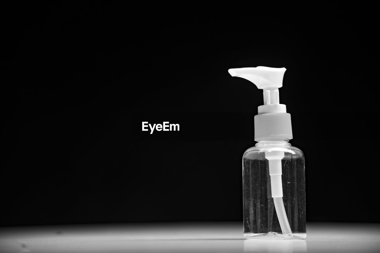 Close-up of spray bottle on table against black background