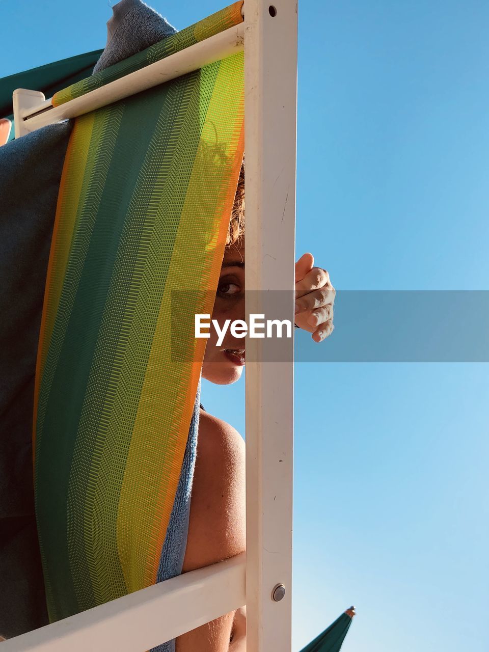 Low angle view portrait of woman sitting on lounge chair against sky