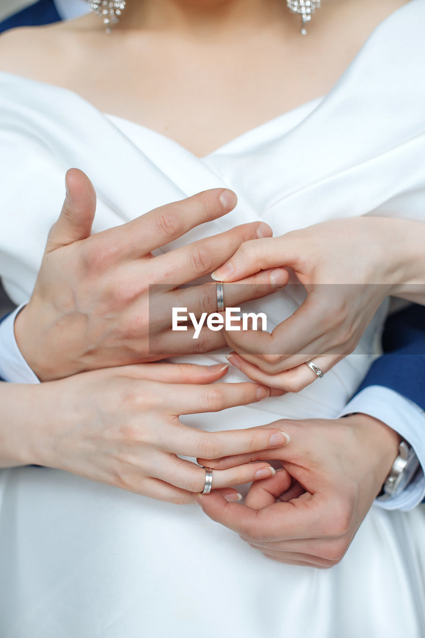 midsection of bride and groom holding hands