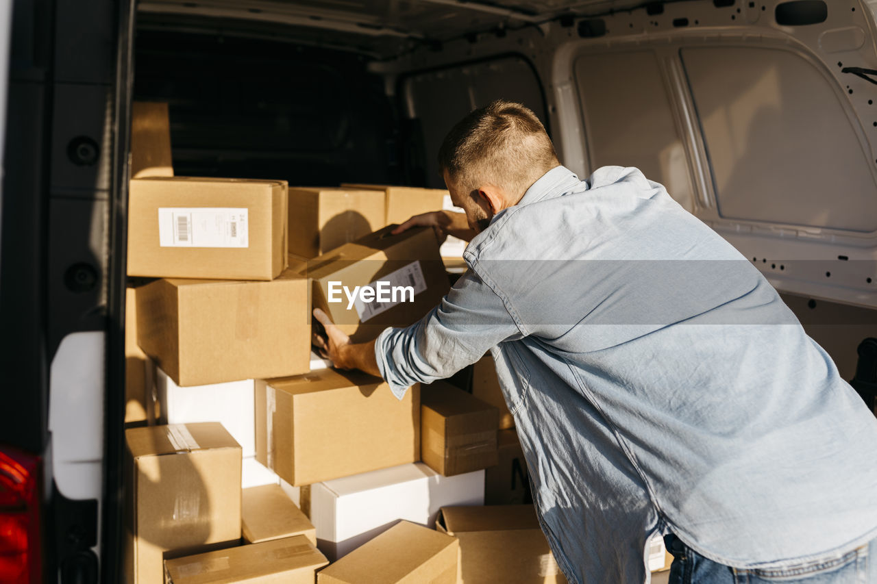 Young delivery man arranging packages in van