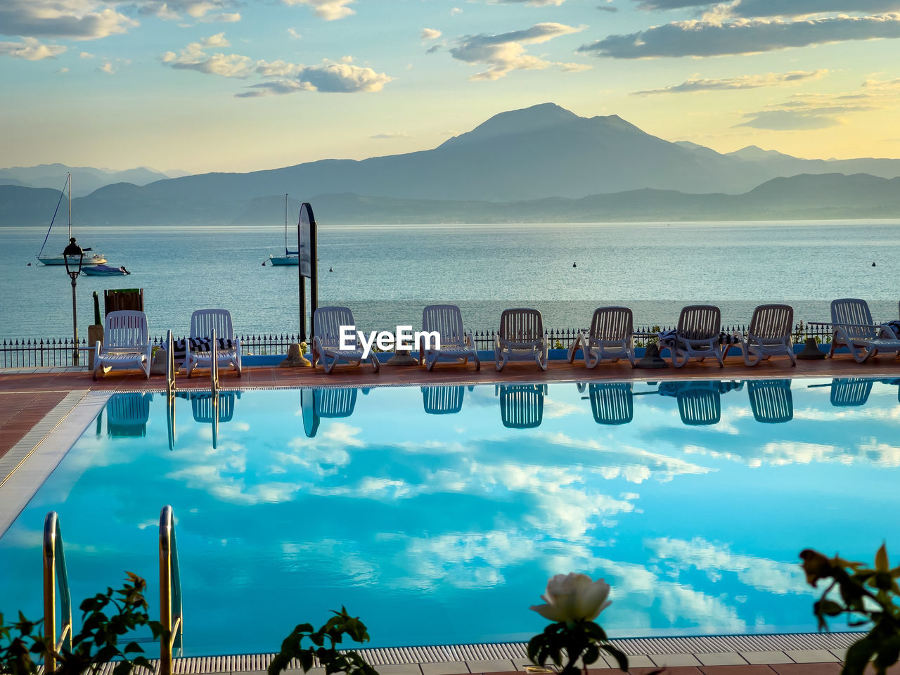 SCENIC VIEW OF SWIMMING POOL BY SEA AGAINST SKY DURING SUNSET