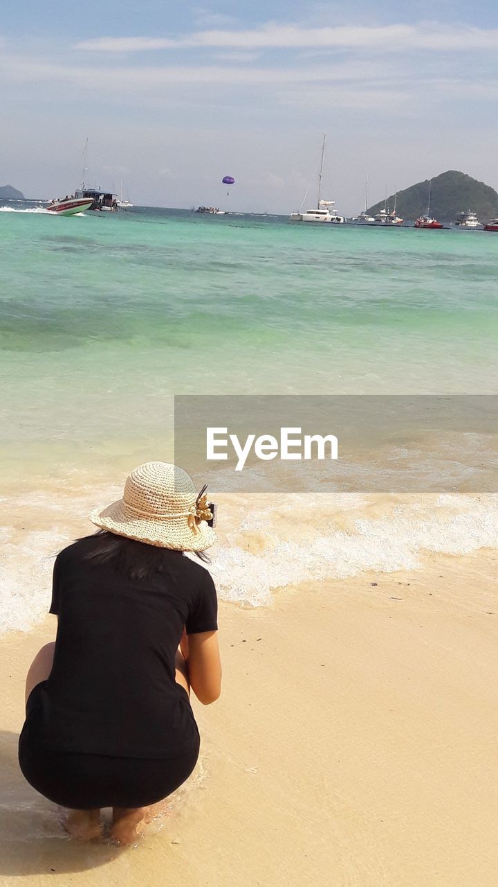 REAR VIEW OF WOMAN LOOKING AT SEA SHORE