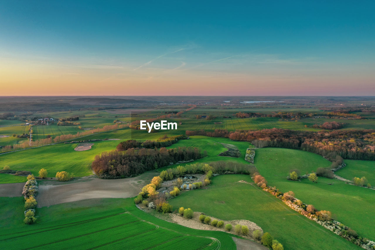 SCENIC VIEW OF GRASSY FIELD AGAINST SKY DURING SUNSET