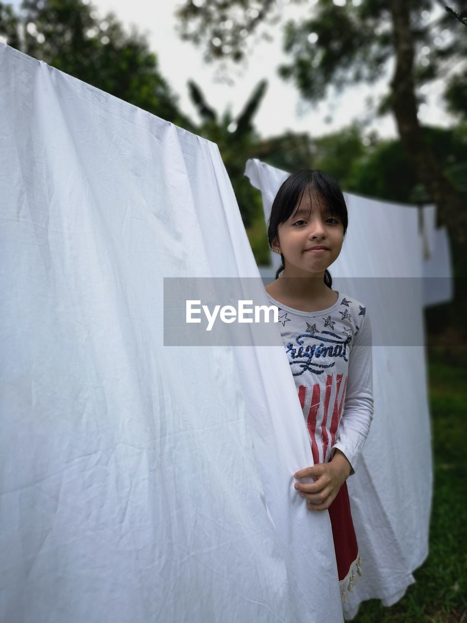 Portrait of girl standing by clothes drying on clothesline