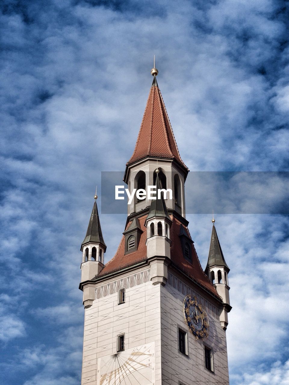 High section of clock tower against blue sky and clouds
