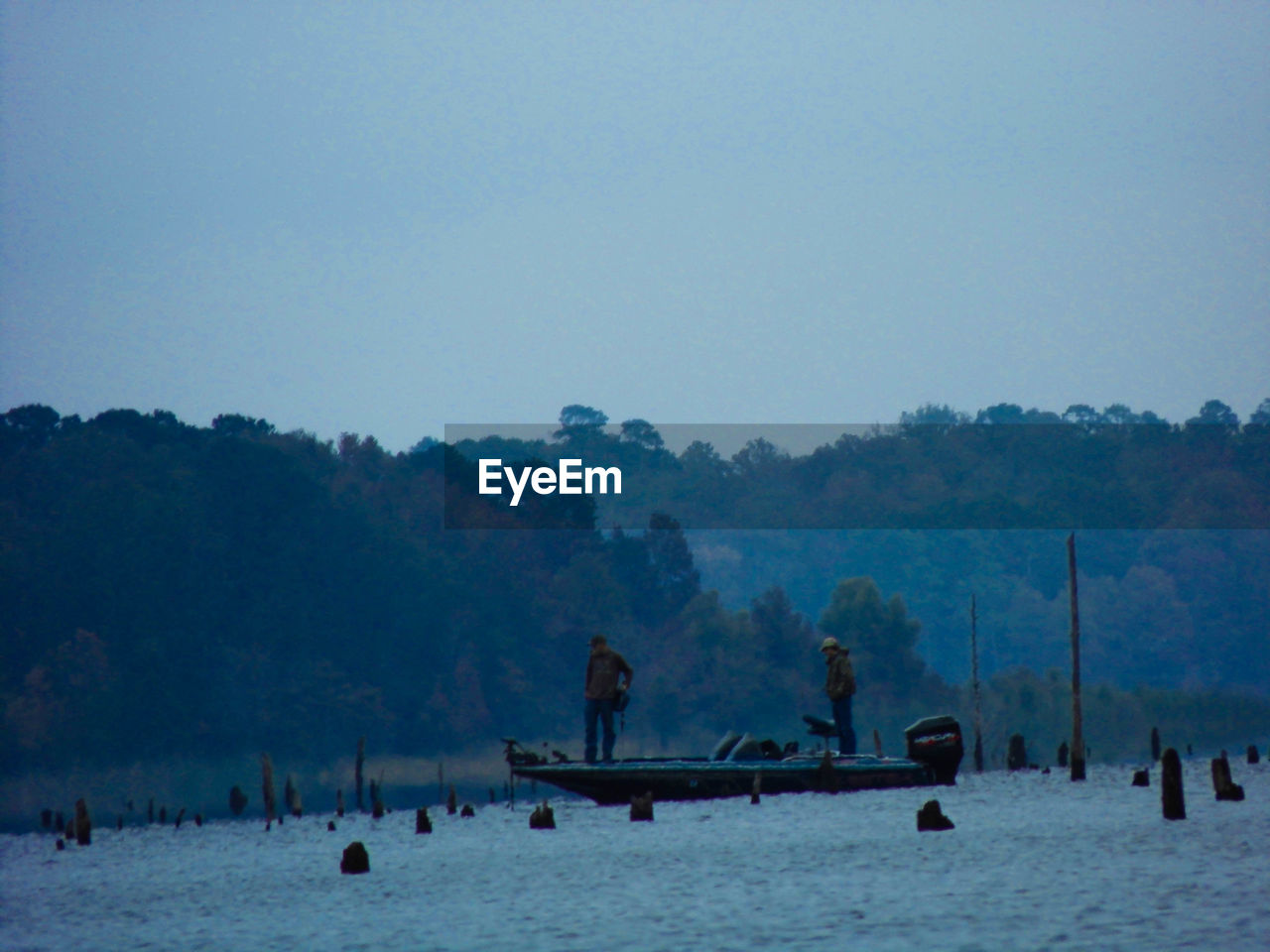 Men on boat in lake against clear sky