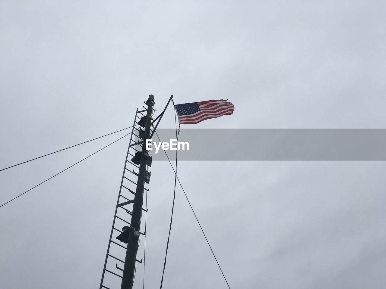 Low angle view of american flag by pole against sky