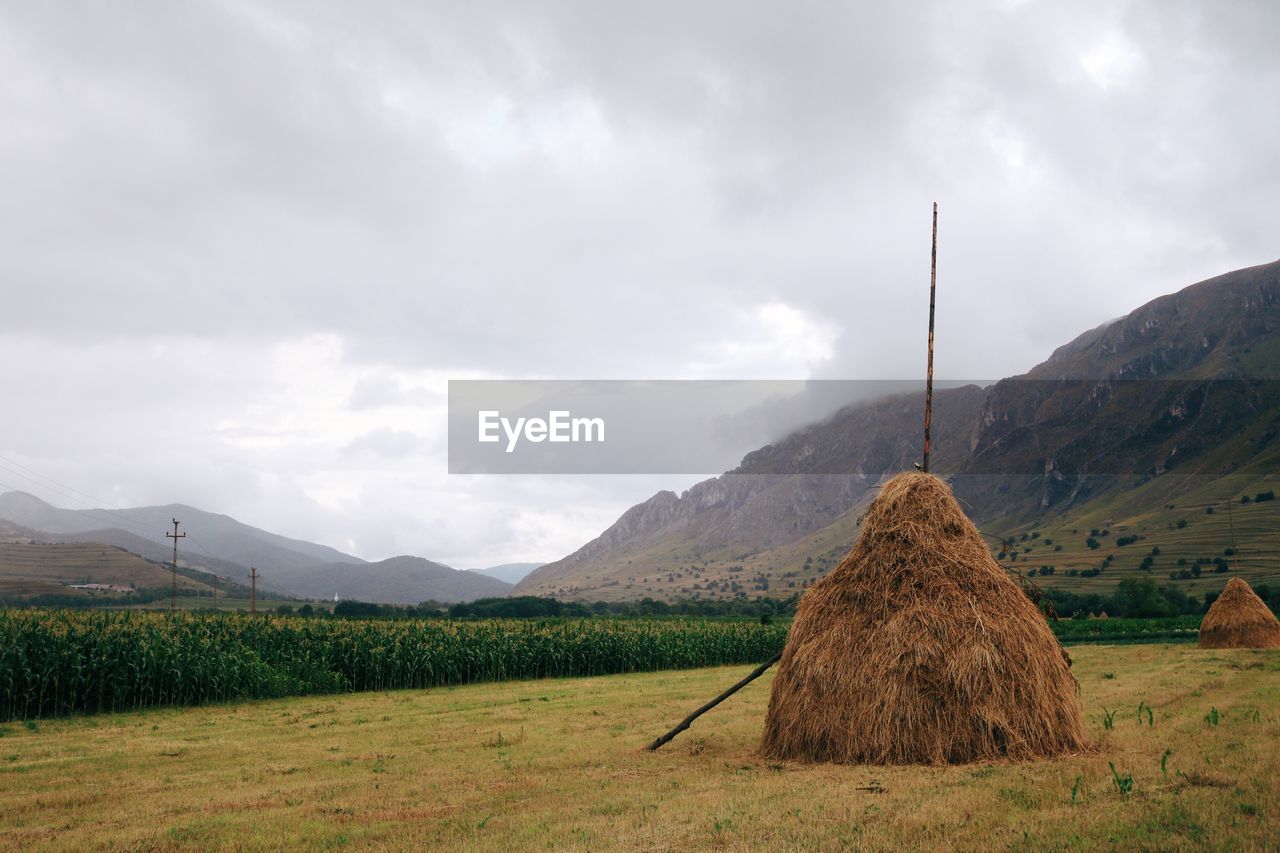 Hay bales on field against cloudy sky