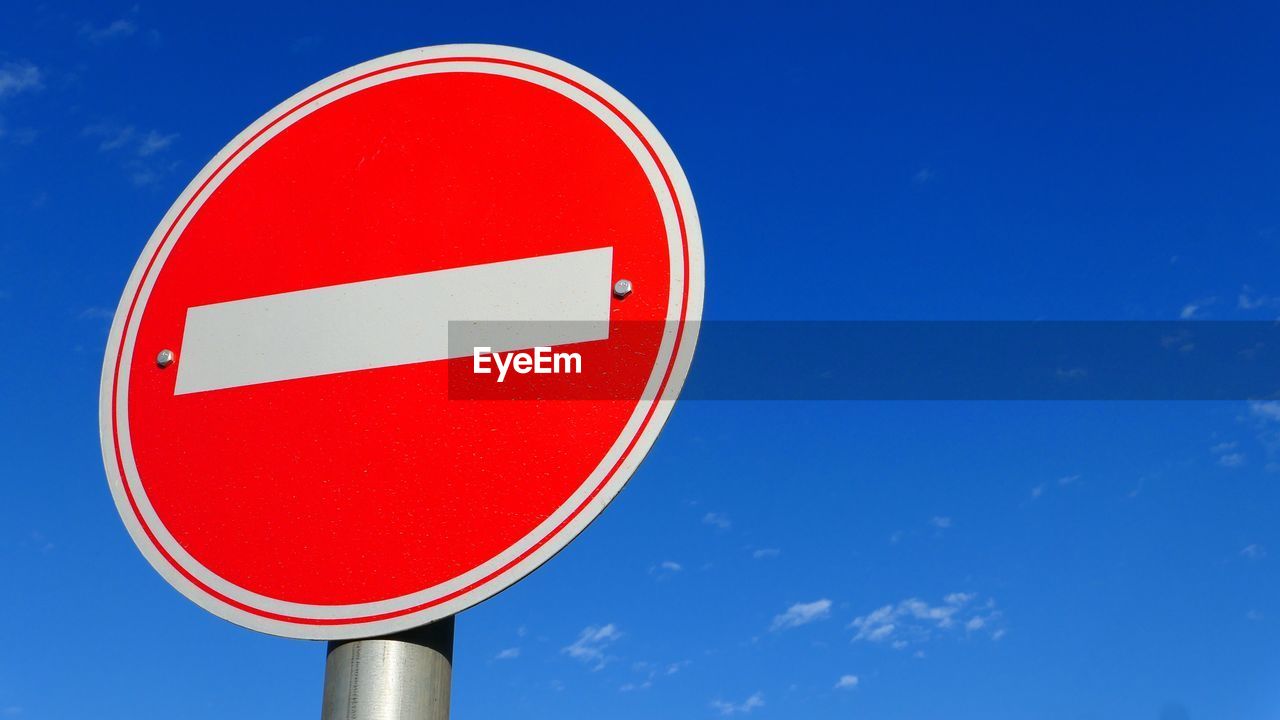 Close-up of road sign against blue sky