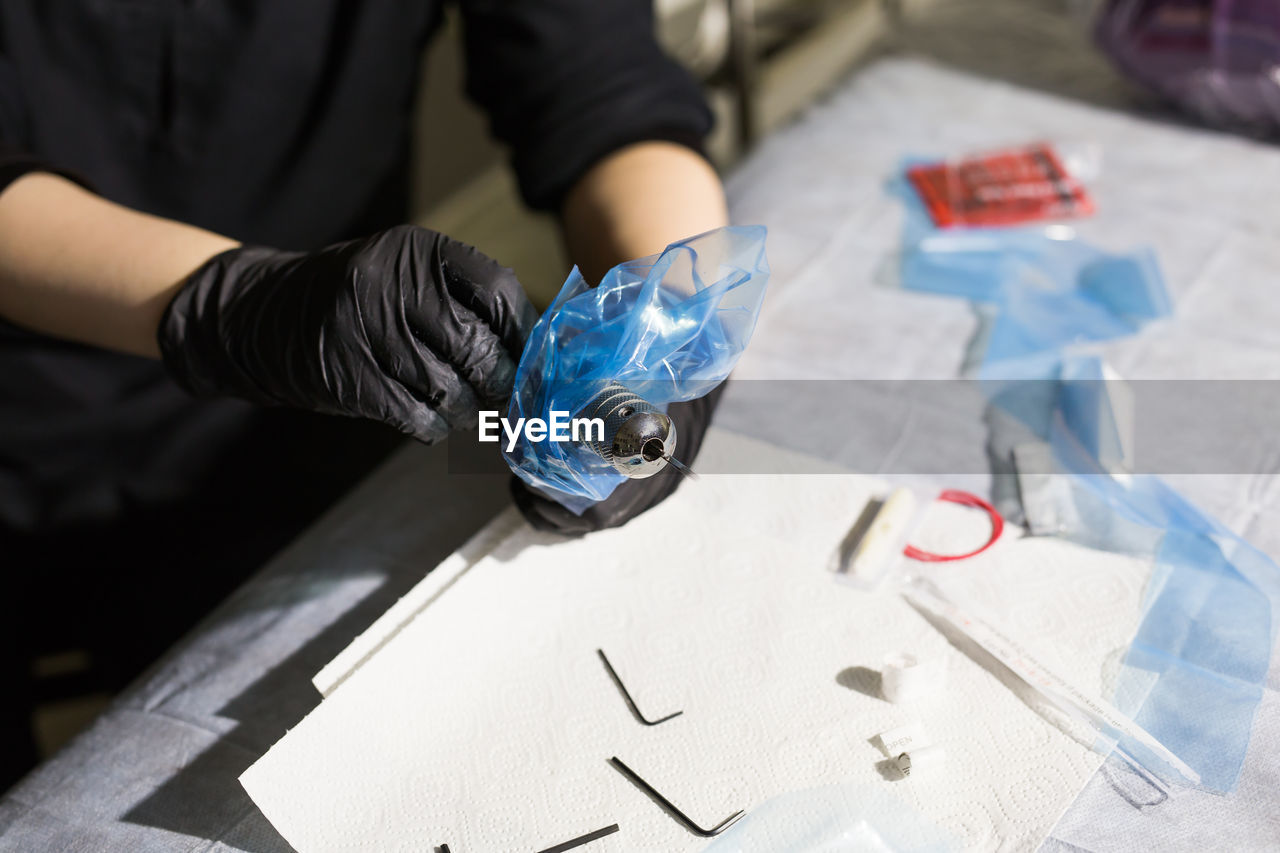 HIGH ANGLE VIEW OF PERSON WORKING ON TABLE WITH HANDS