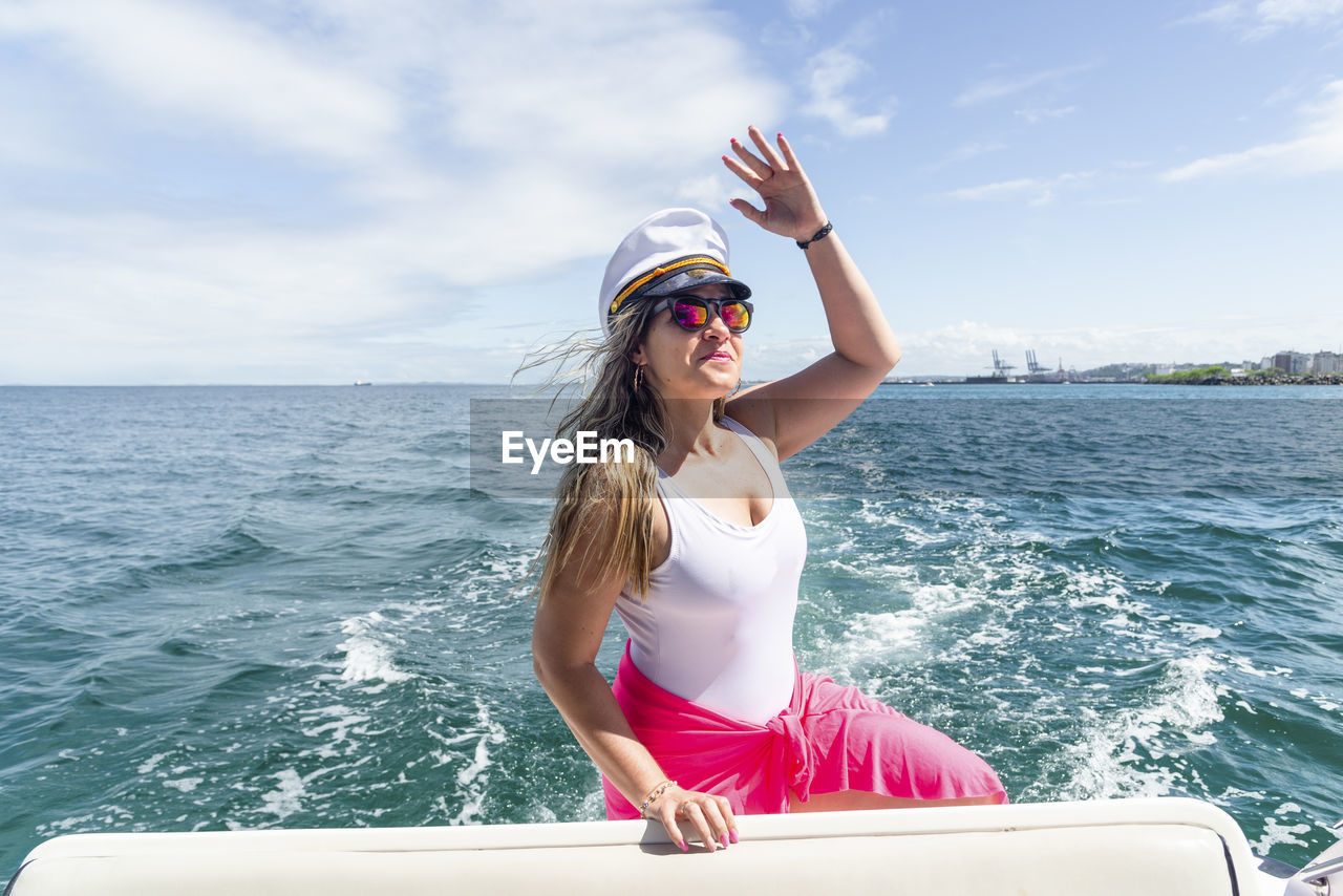 Side view of woman sitting on boat in sea against sky