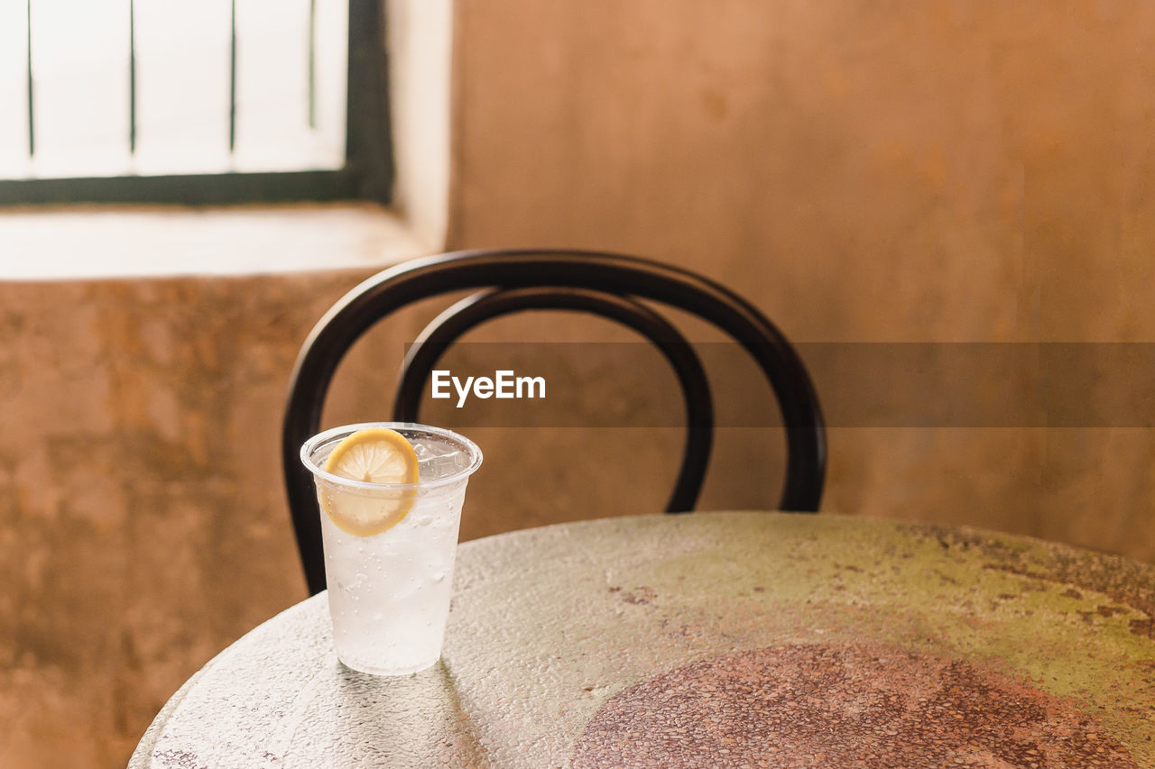 Glass of sparkling water with slice of lemon on table at home