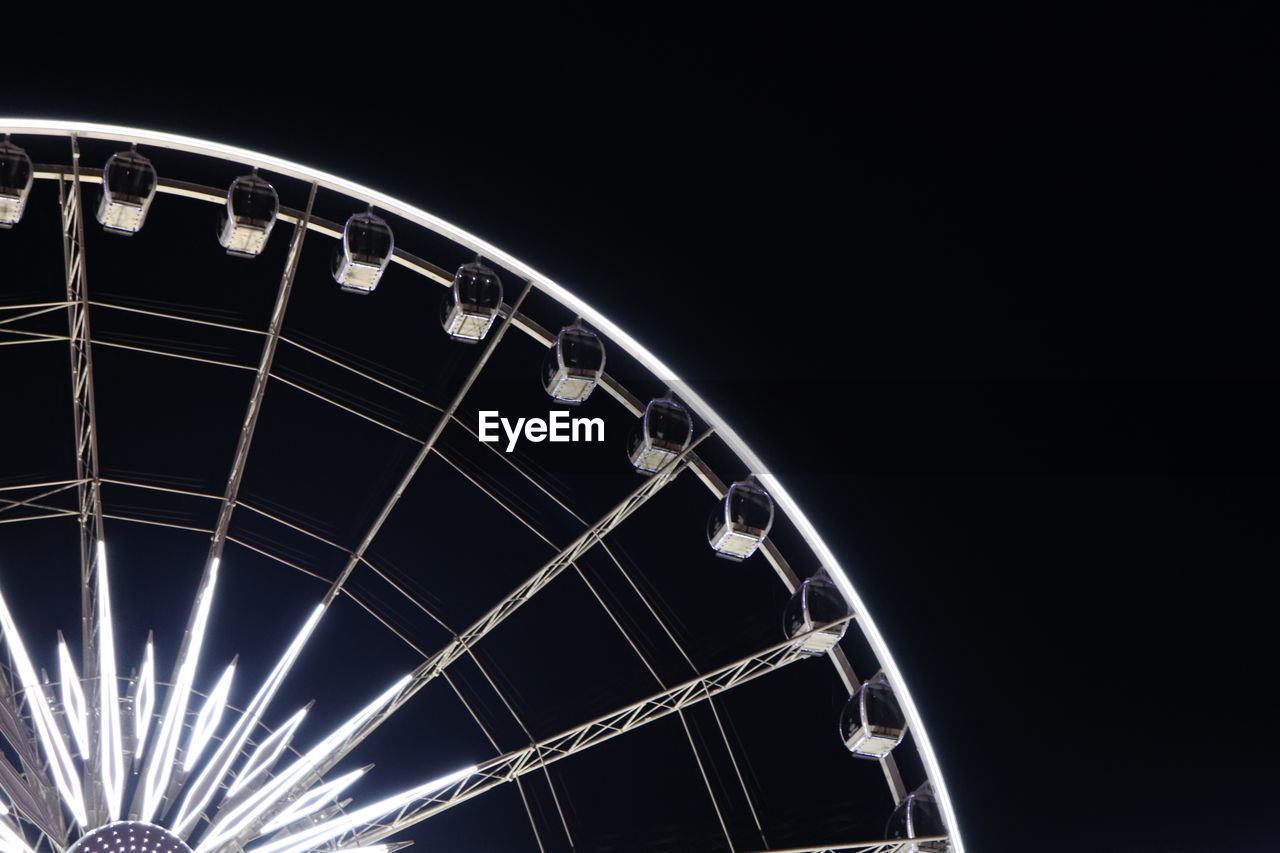 LOW ANGLE VIEW OF FERRIS WHEEL AGAINST CLEAR SKY AT NIGHT