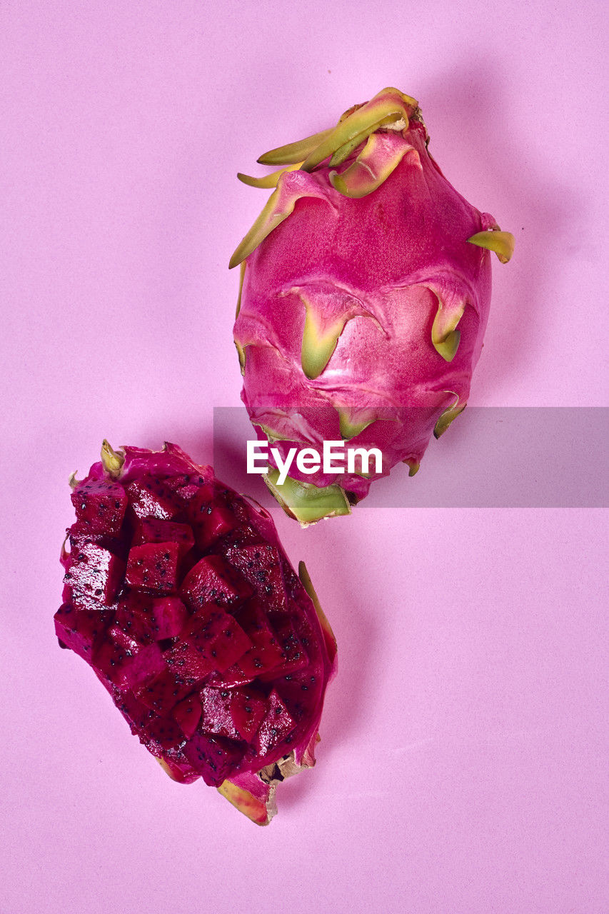Red dragon fruit set with appetizing serving isolated on pink background. top view, hand