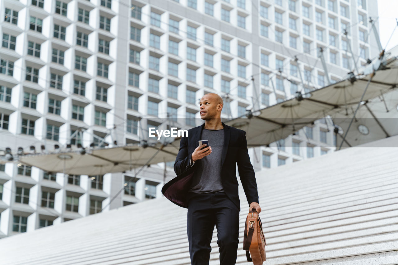 portrait of businessman standing against building in city