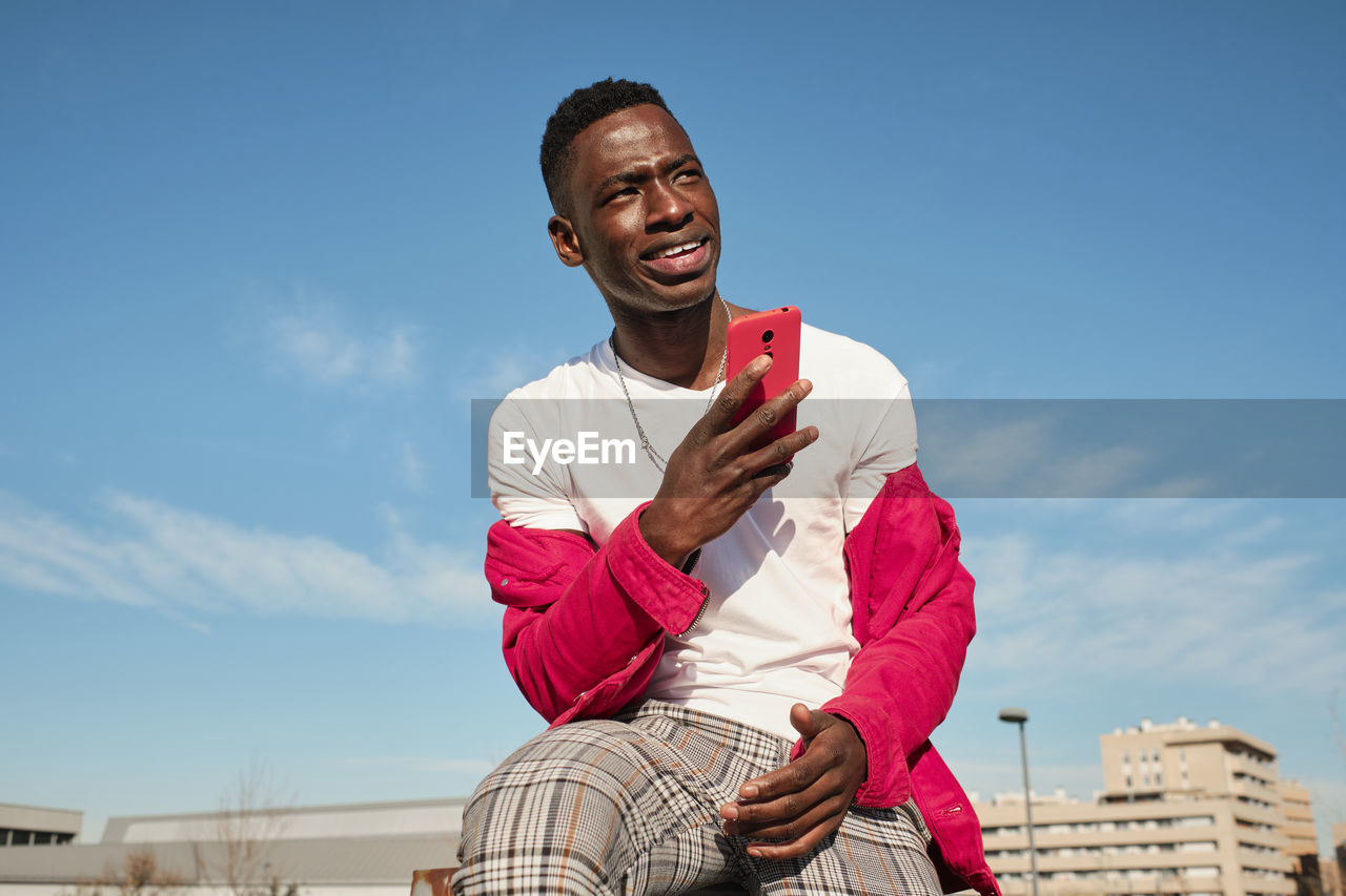 Young man in red jacket looking at smart phone outdoors