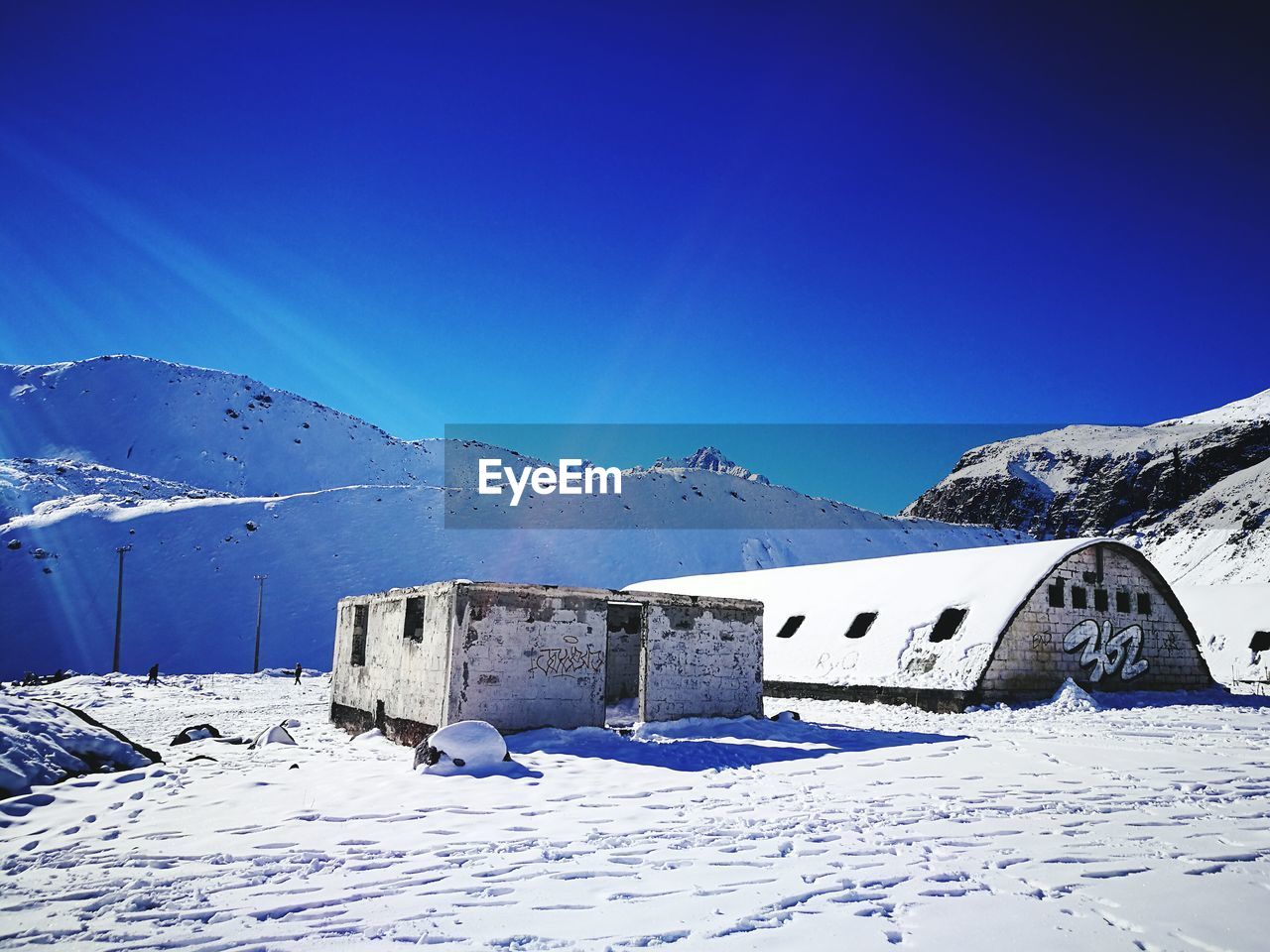 Built structure on snowcapped mountain against blue sky