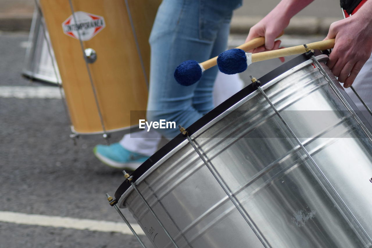 Cropped image of hands playing drum on street