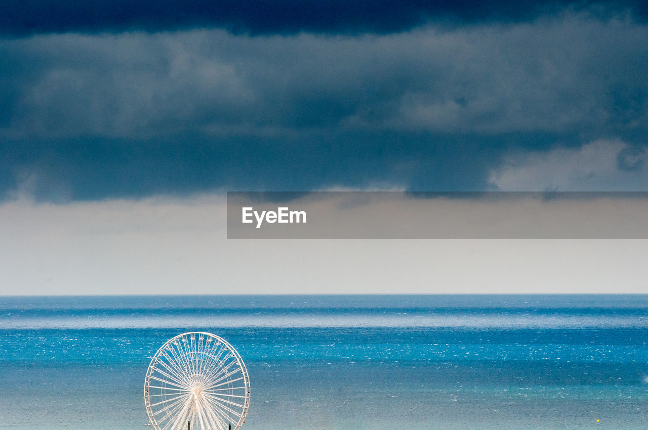 High angle view of ferris wheel against cloudy sky