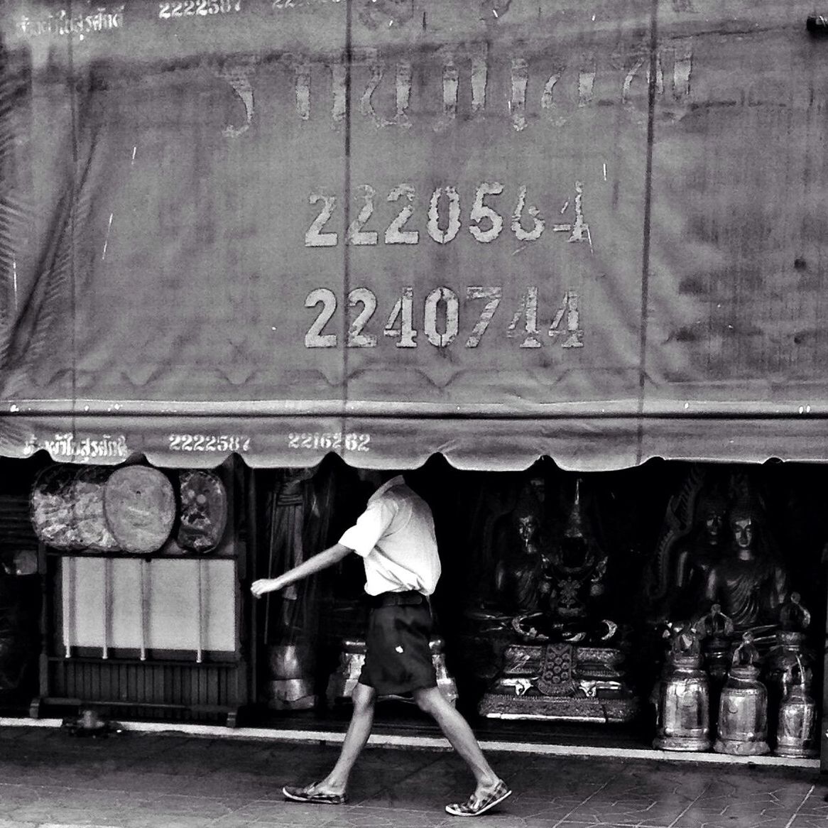 Man walking on footpath against store