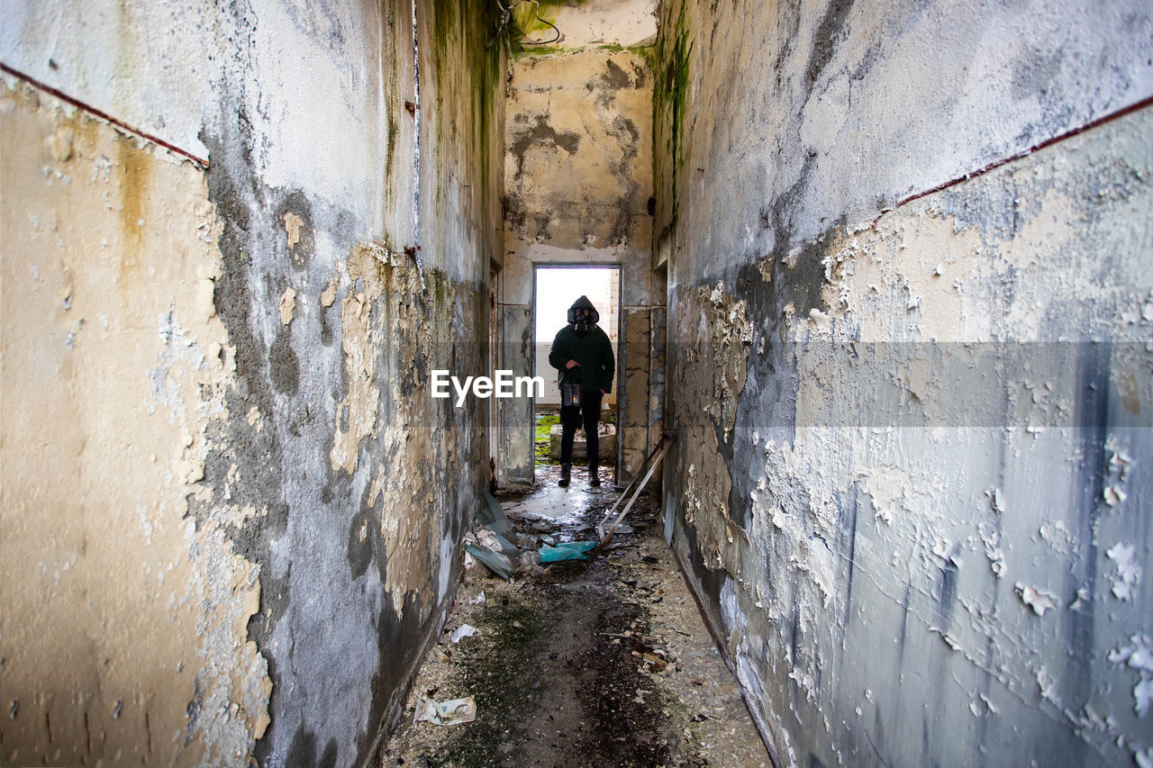 REAR VIEW OF MAN STANDING ON OLD BUILDING WALL