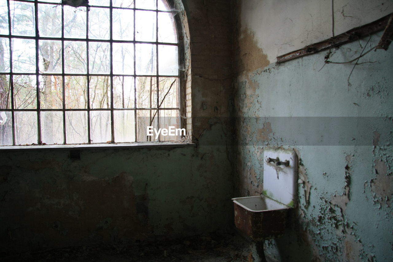 Old sink by window of abandoned house