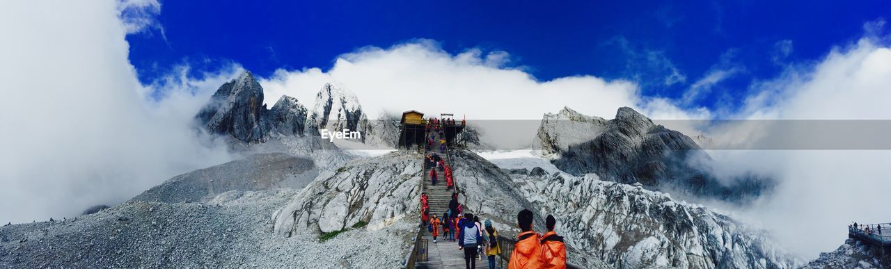 Panoramic view of people on staircase at mountain peak against sky