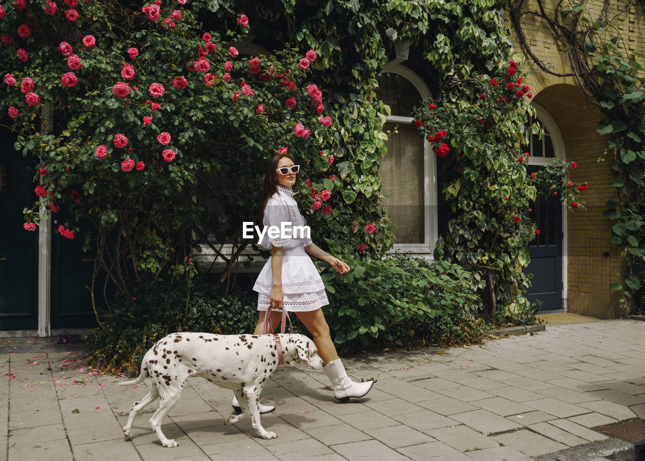 Portrait of woman standing by plants with dog