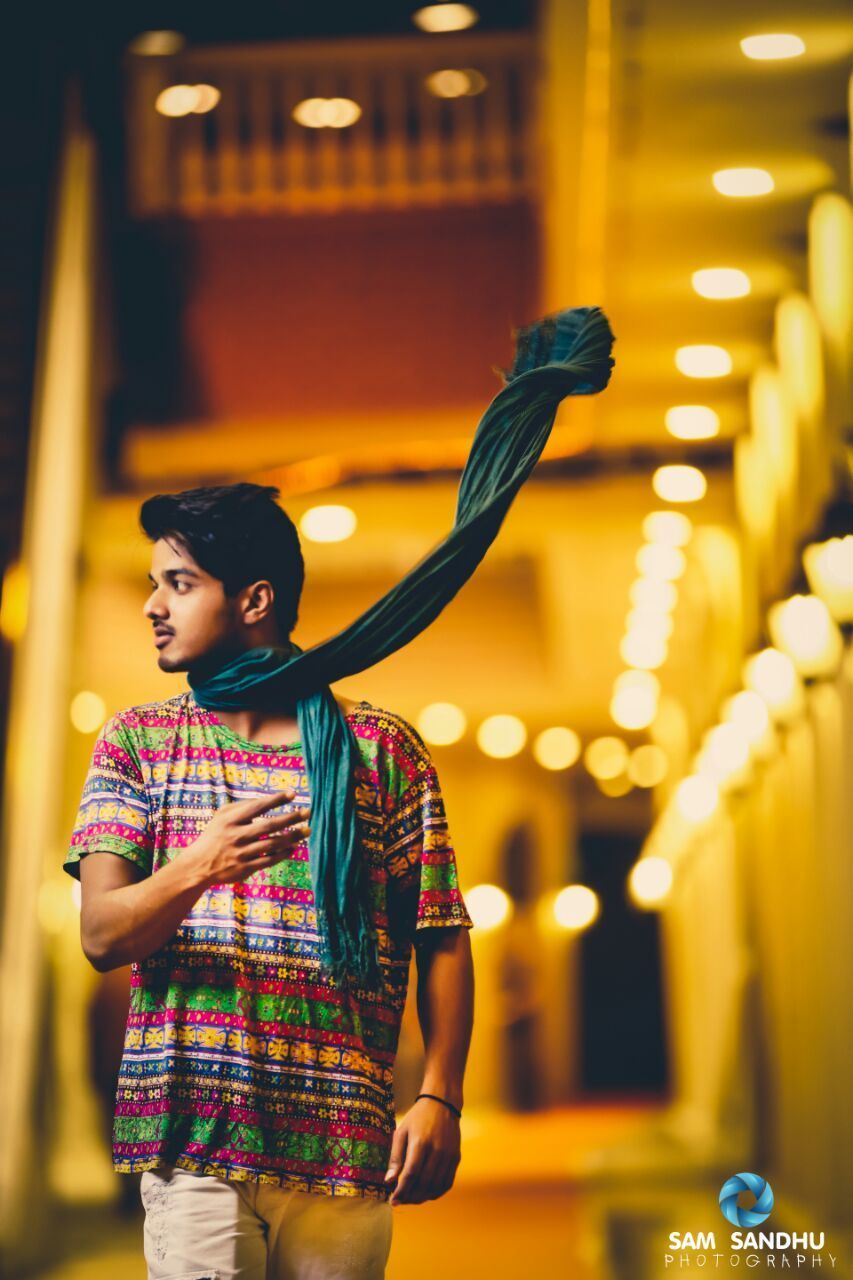 Young man wearing shawl against illuminated building at night