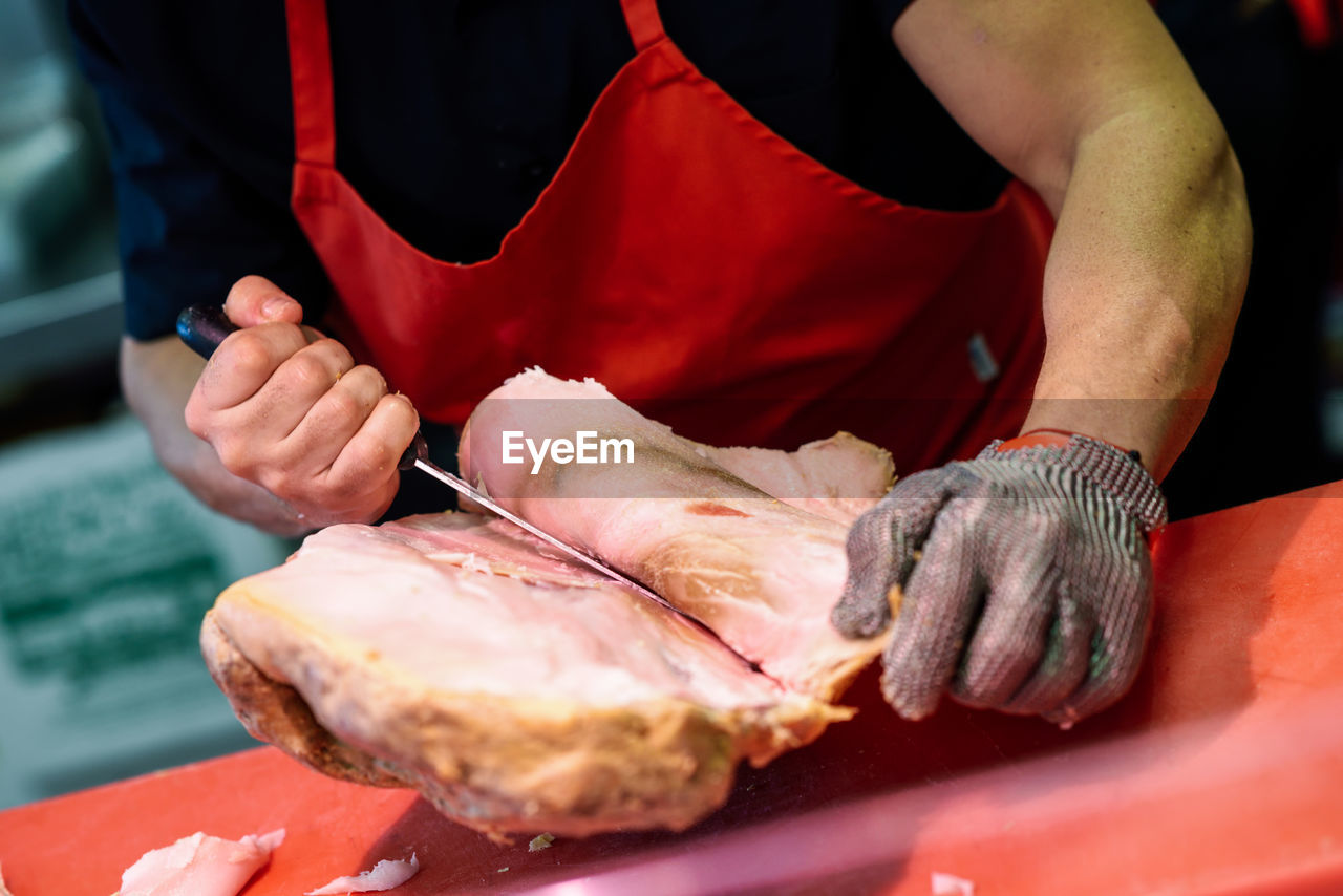 Midsection of chef cutting meat in kitchen