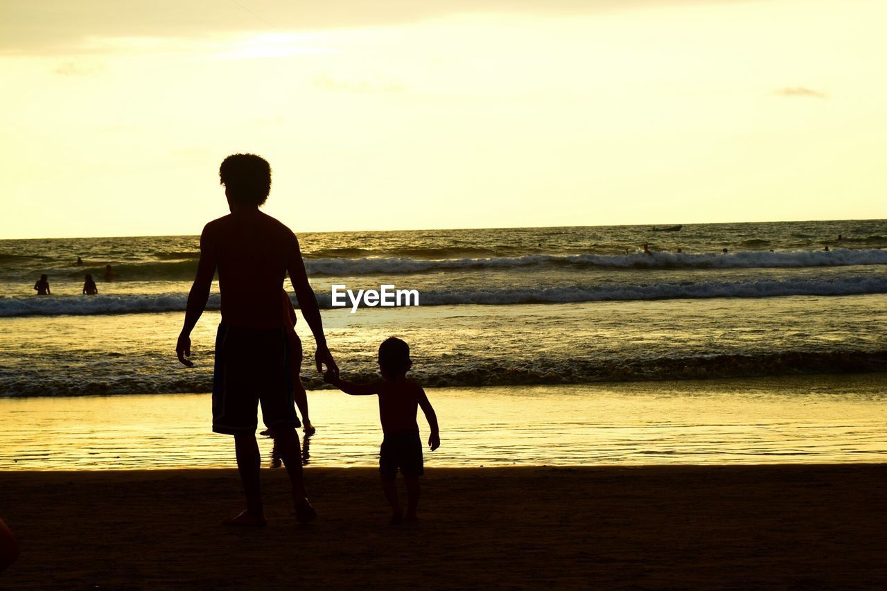 Rear view of people walking on beach