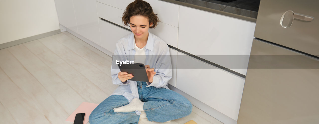 low angle view of young woman sitting on floor at home