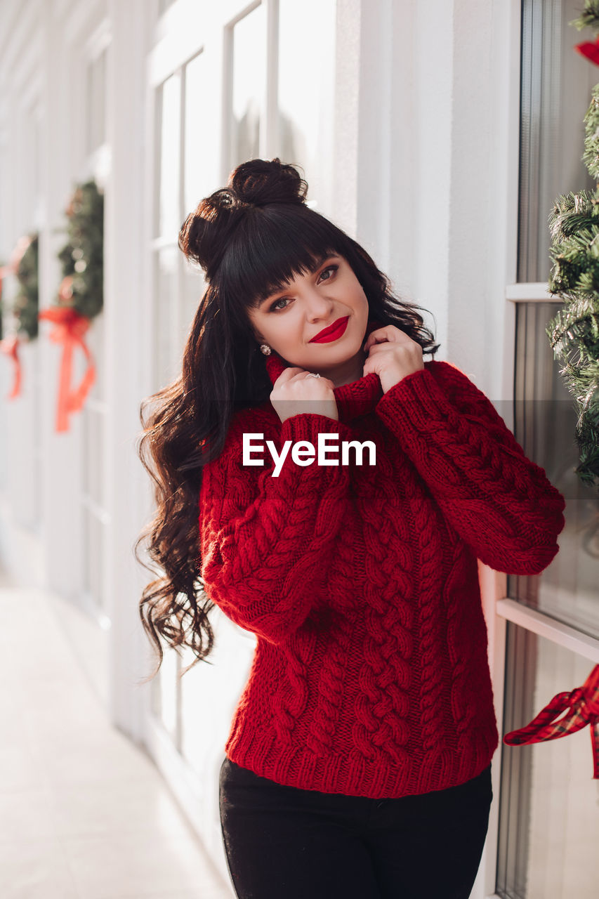 Portrait of a young woman in a warm knitted red sweater outside