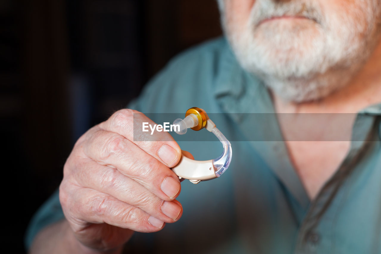Midsection close-up of man holding hearing aid