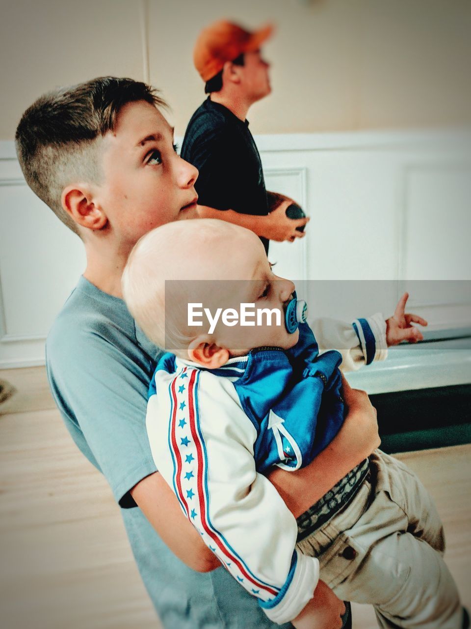 Boy carrying brother on hardwood floor