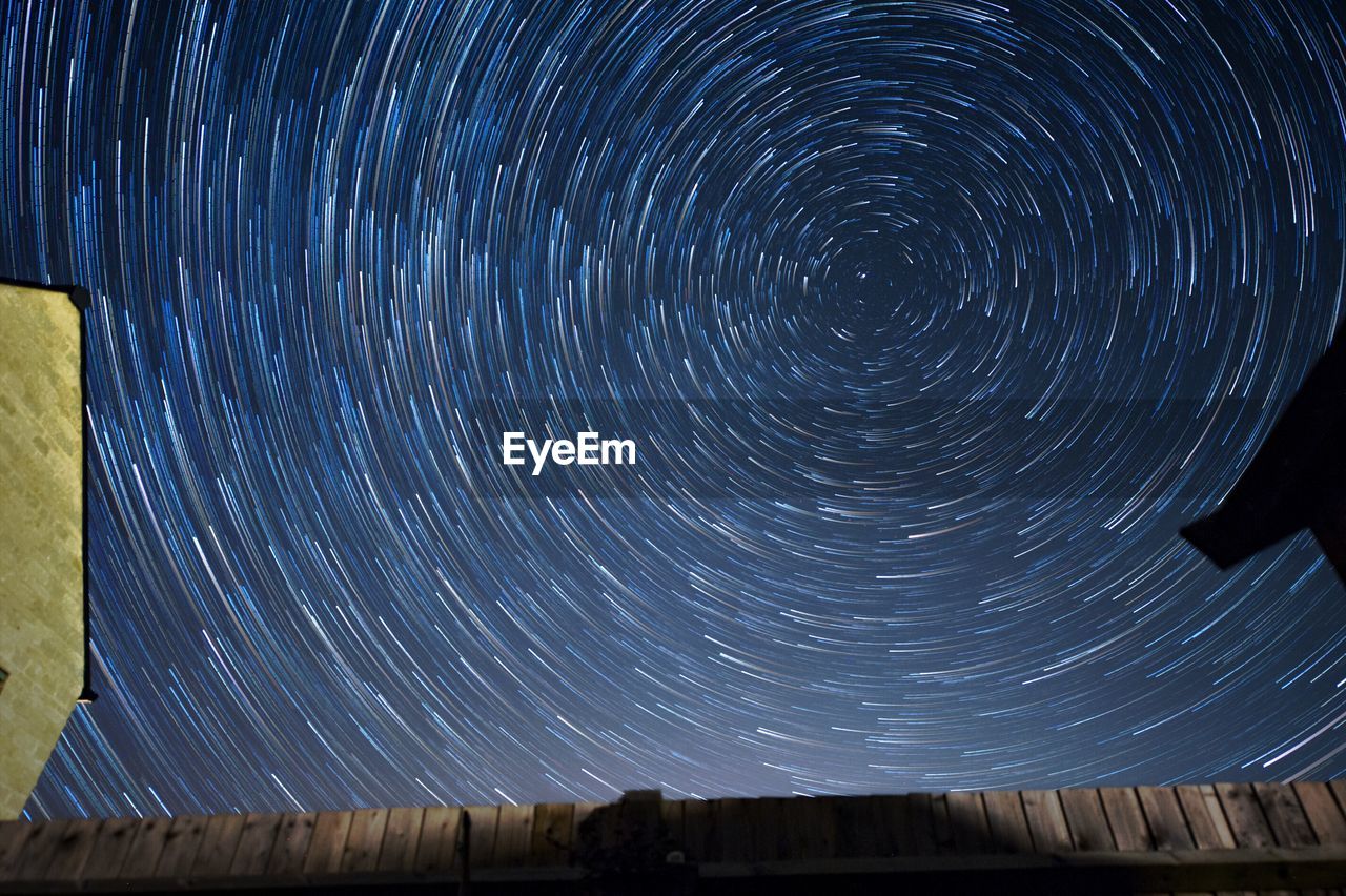 LOW ANGLE VIEW OF STAR TRAILS AGAINST SKY AT NIGHT