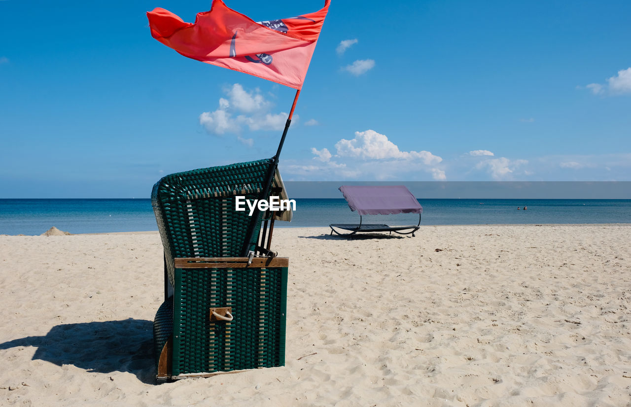 Deck chairs on beach against sky