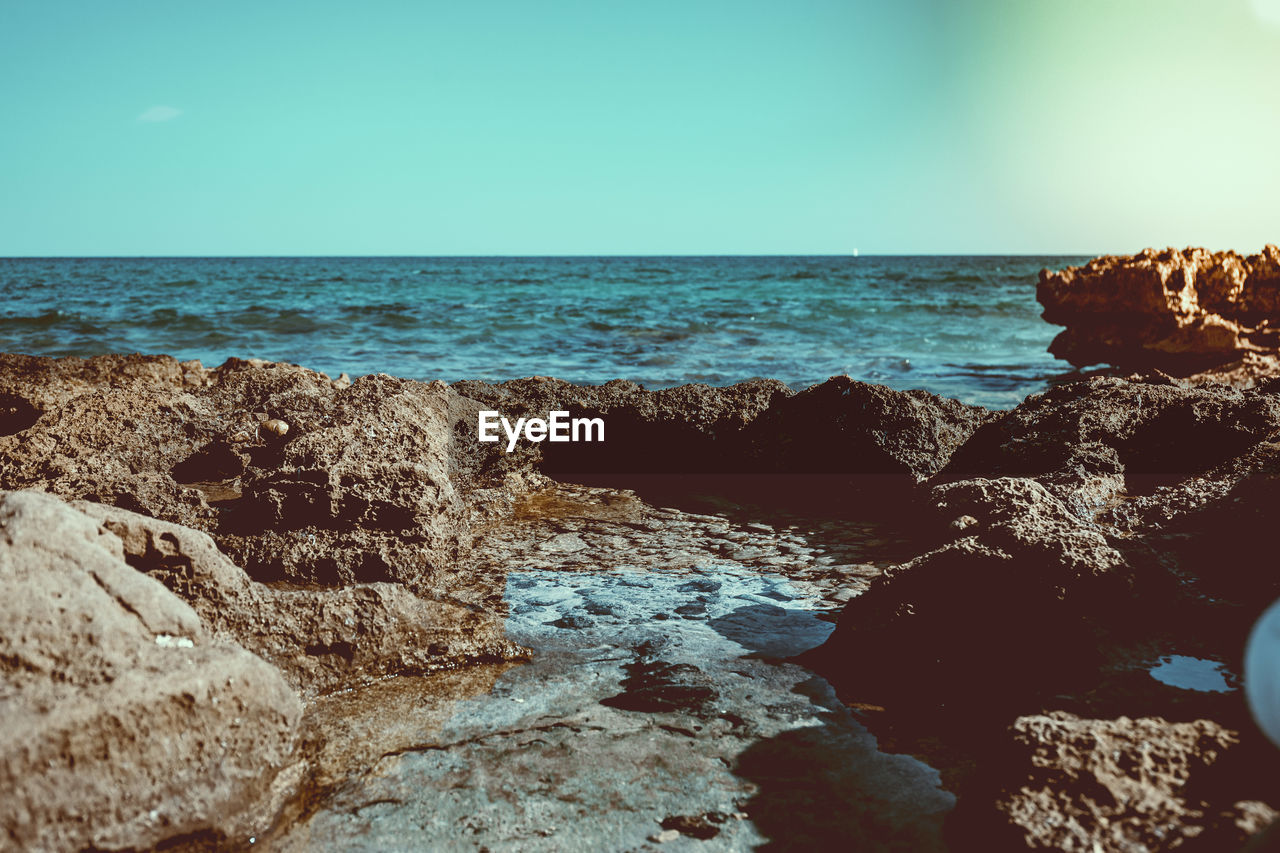 Close-up of rocks in sea against clear sky