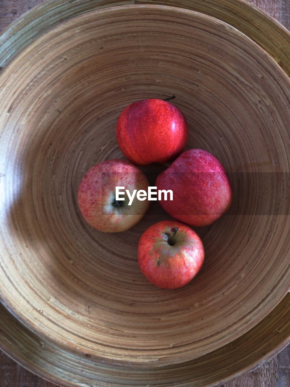 Four apples in a wooden bowl