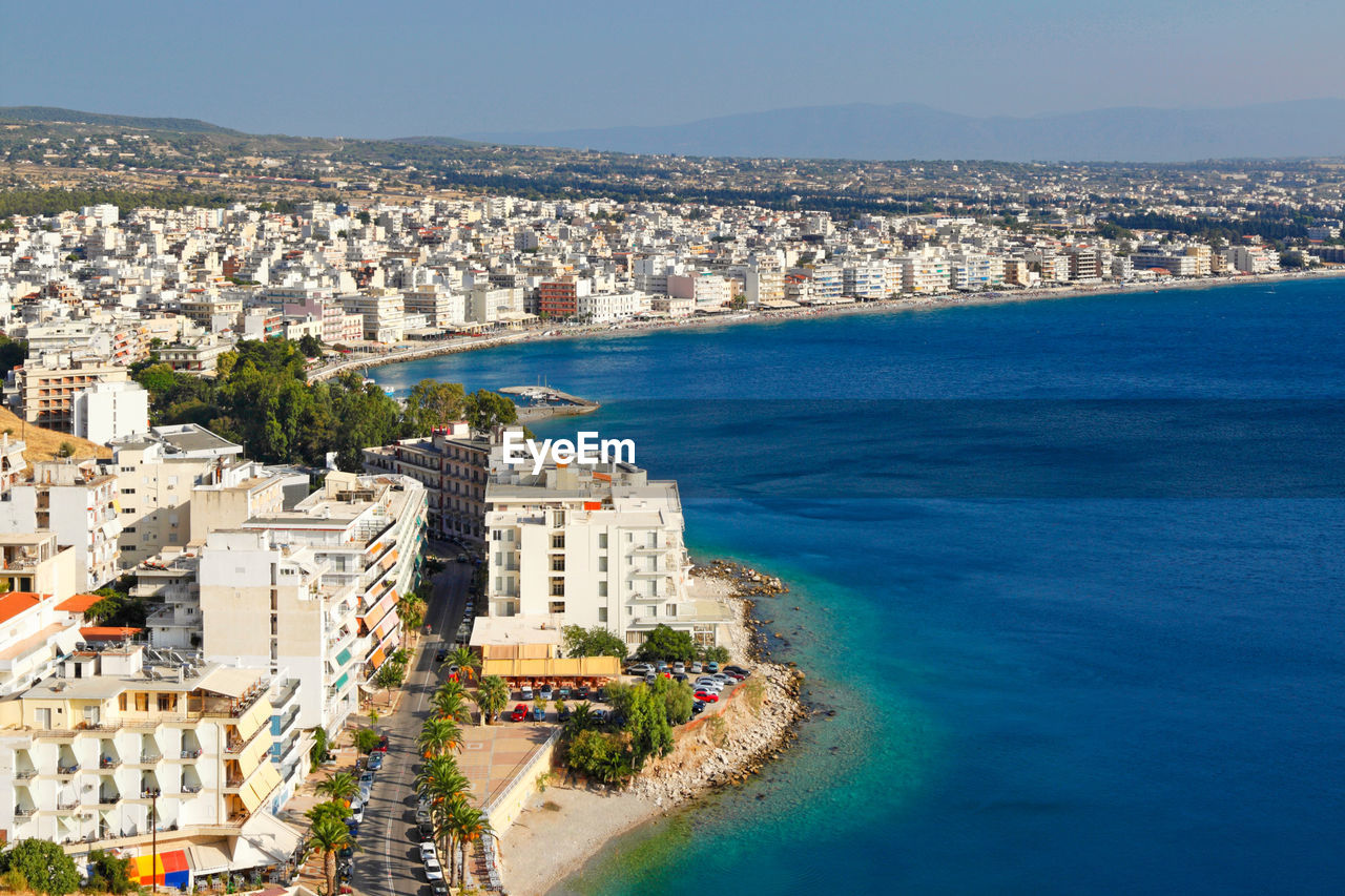 HIGH ANGLE VIEW OF SEA AND BUILDINGS IN CITY