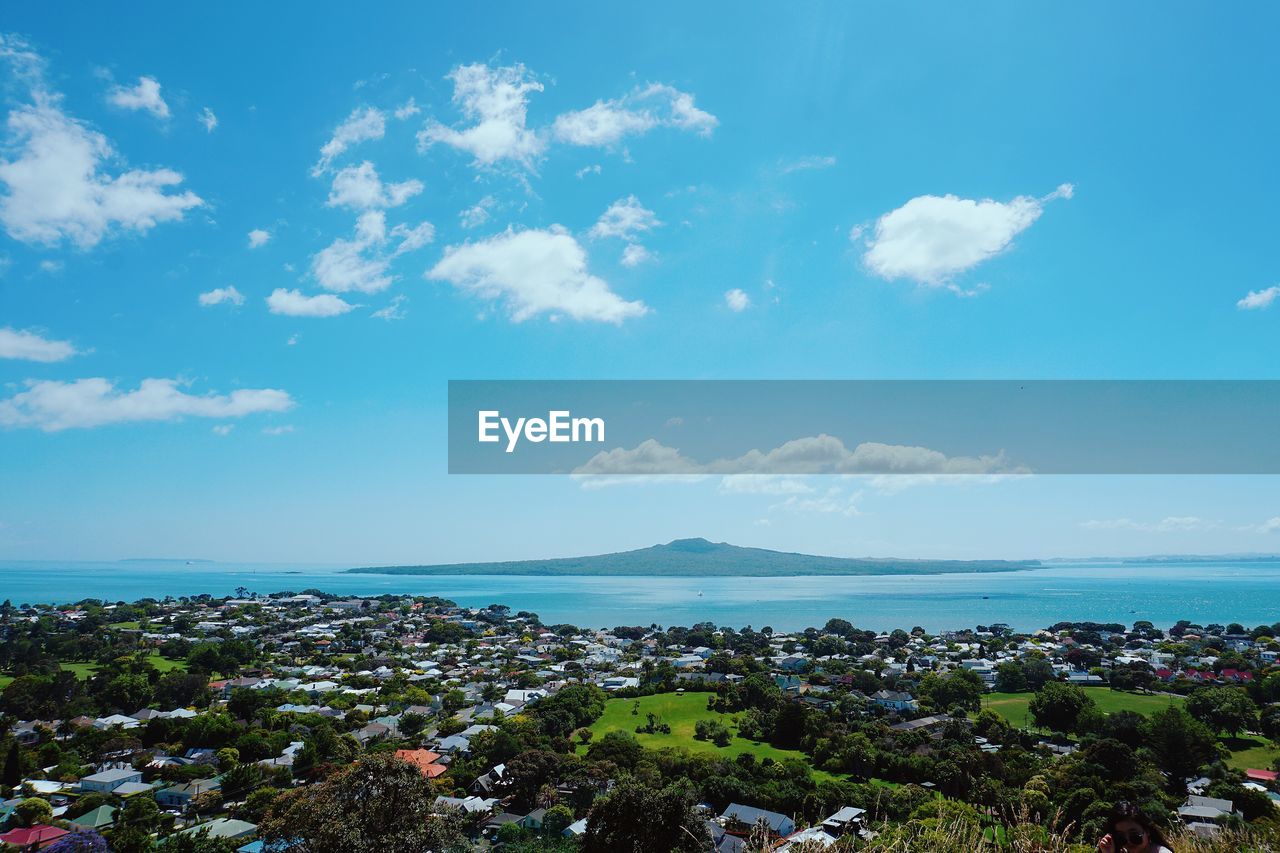 Aerial view of city by sea against blue sky