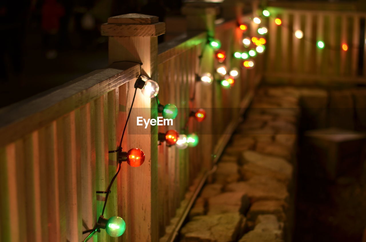Multi colored illuminated light bulbs decorated on railing at night