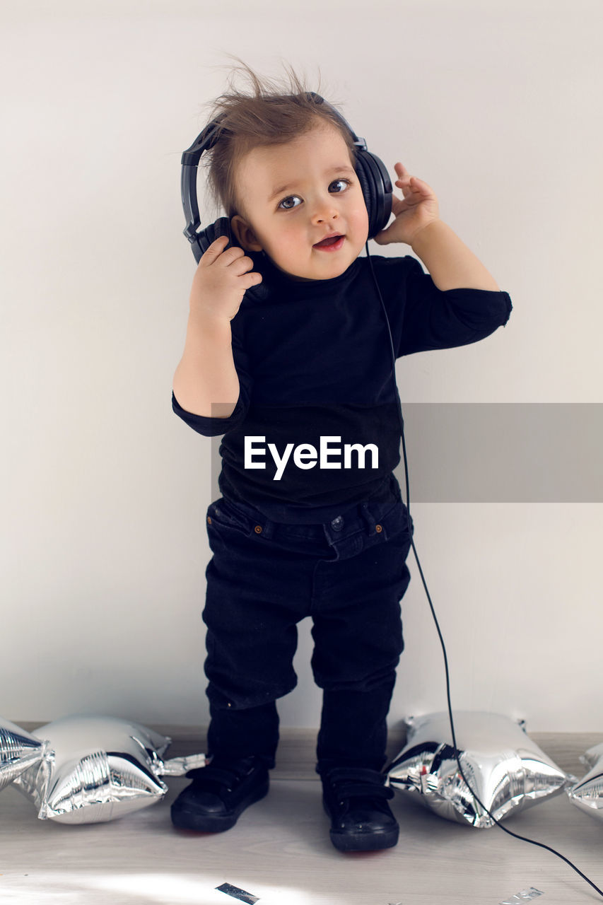 One-year-old baby in black clothes listening to rock music in big headphones