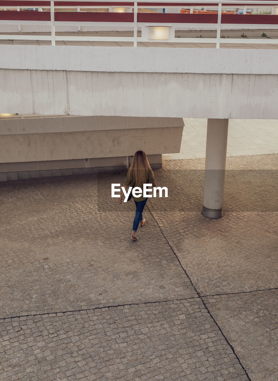 Rear view of woman walking on footpath in city