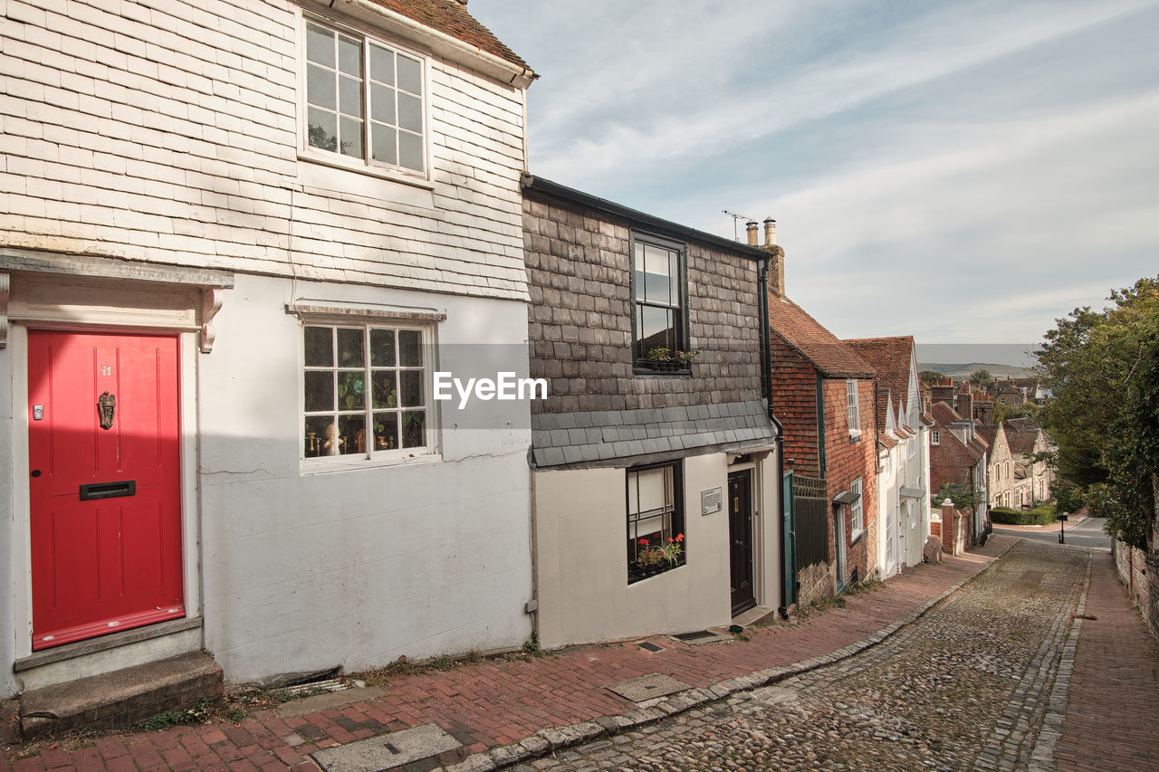 View down historic cobbled keere street with bright red front door in foreground lewes sussex uk