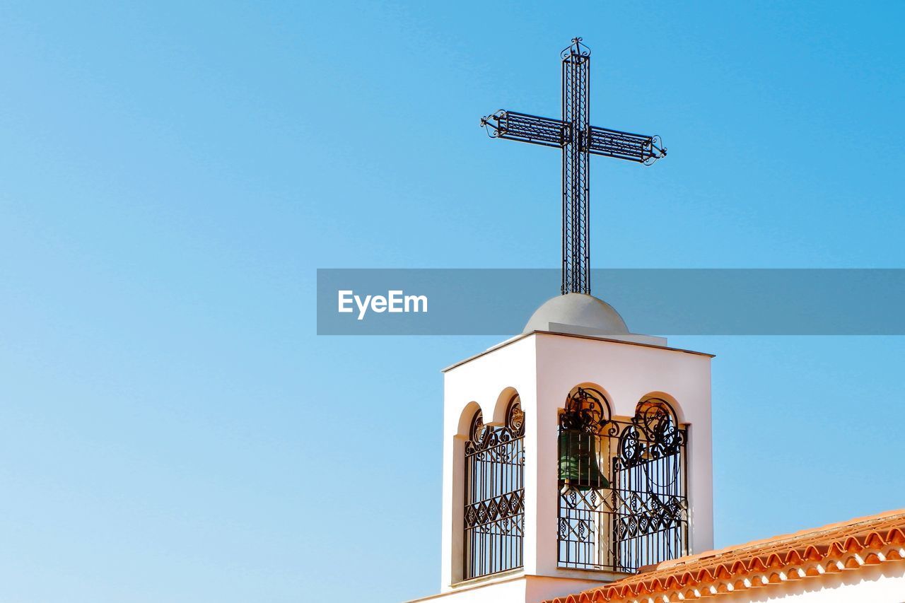 LOW ANGLE VIEW OF CROSS AND BUILDING AGAINST CLEAR SKY