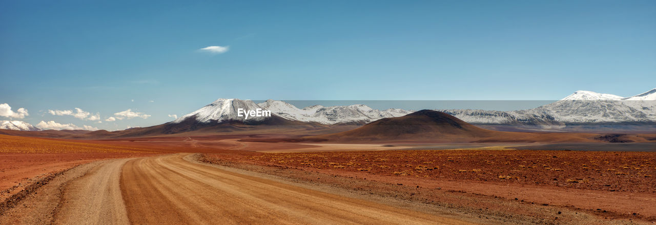 Scenic view of road by mountains against sky