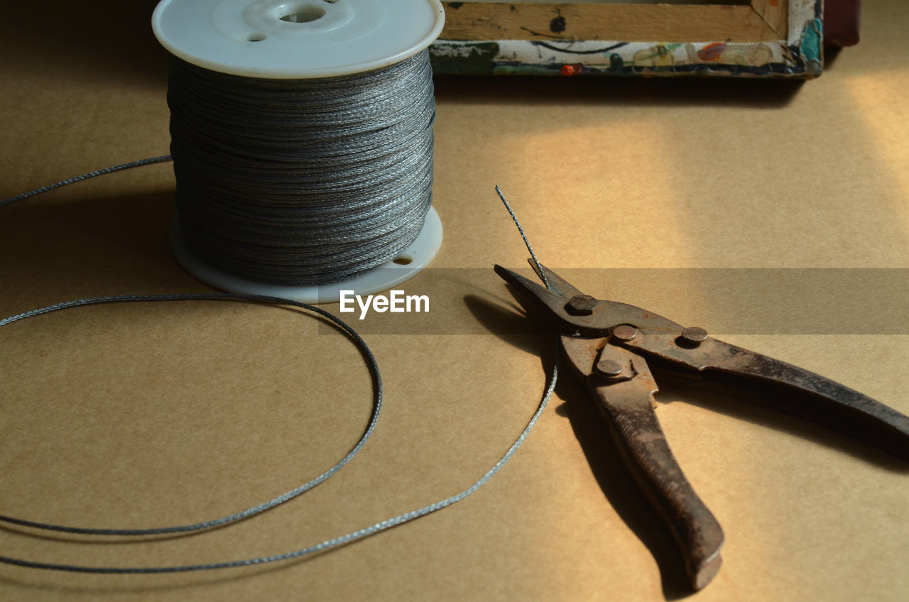 High angle view of steel cables and wire cutter on table in workshop